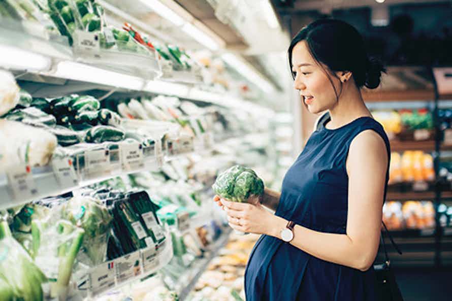 A pregnant woman shopping for healthy food.